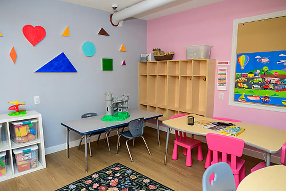 Classroom with pink activity tables and open storage